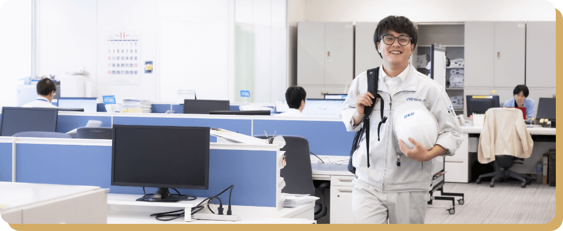 オフィスで笑顔の男性社員が制服姿で立っている様子。船舶業務に関する知識を深め、シーマンシップを体現することを目標に掲げている