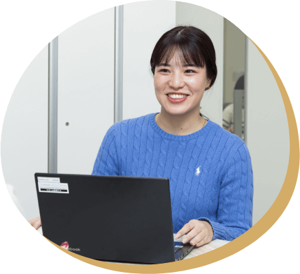 オフィスで笑顔の女性社員がノートパソコンを前に会話をしている様子。職場でのコミュニケーションを通じて成長し、周囲と協力しながら前向きに働く姿勢を身につけた経験を語る